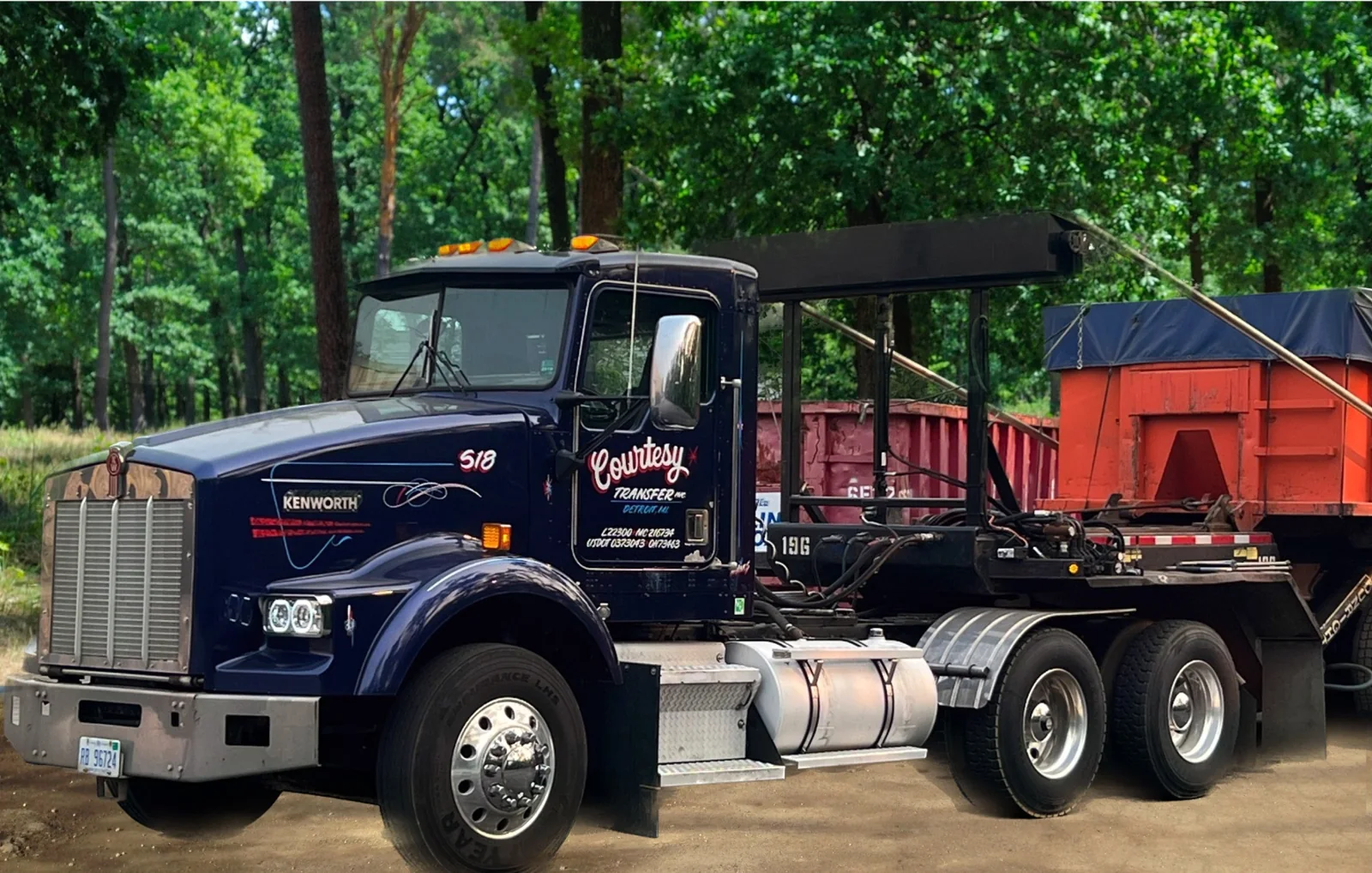 Courtesy Transfer truck carrying a red roll-off container